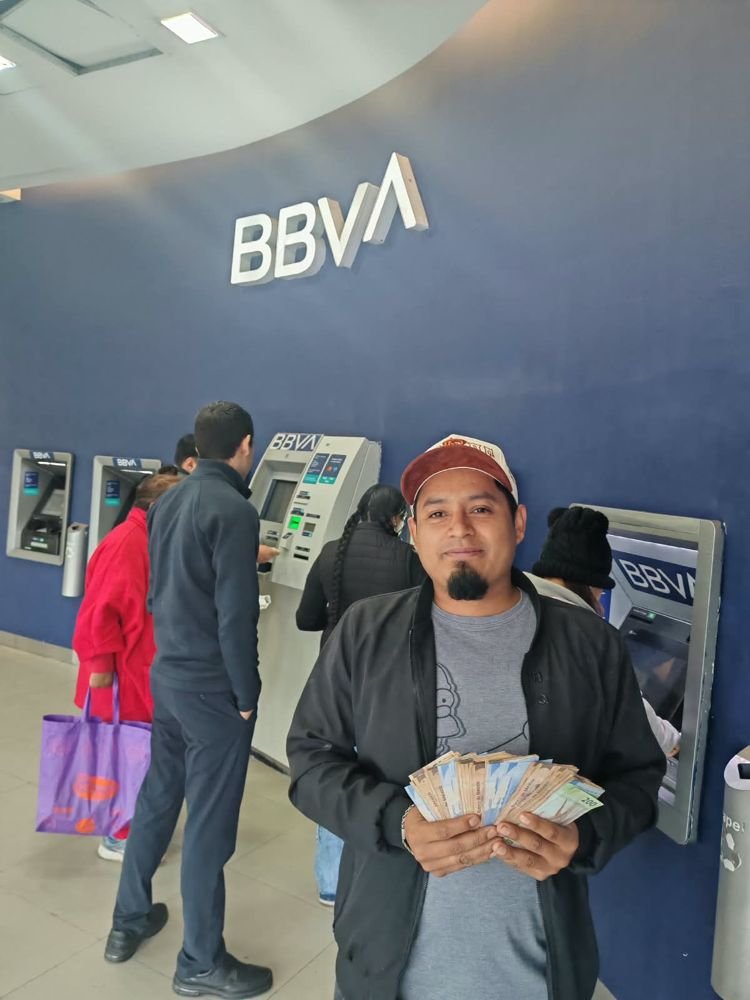 Cliente con su dinero frente a un cajero